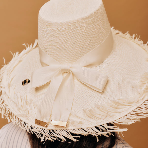 Panama straw hat with fringes and a bow on a brown background
