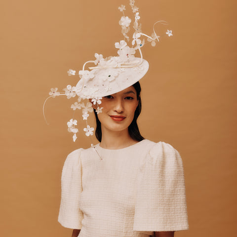 Woman wearing a white floral hat against a brown background