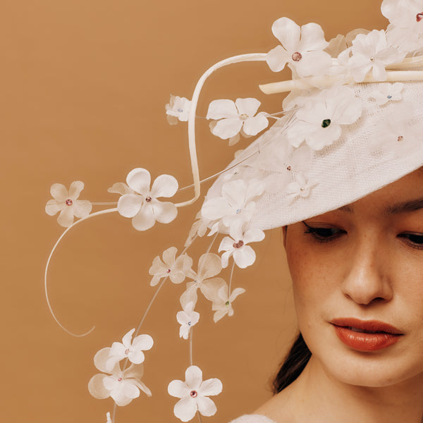 Woman wearing a white floral hat against a brown background