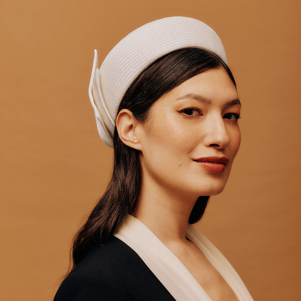 Woman wearing a white headband with a feather against a brown background