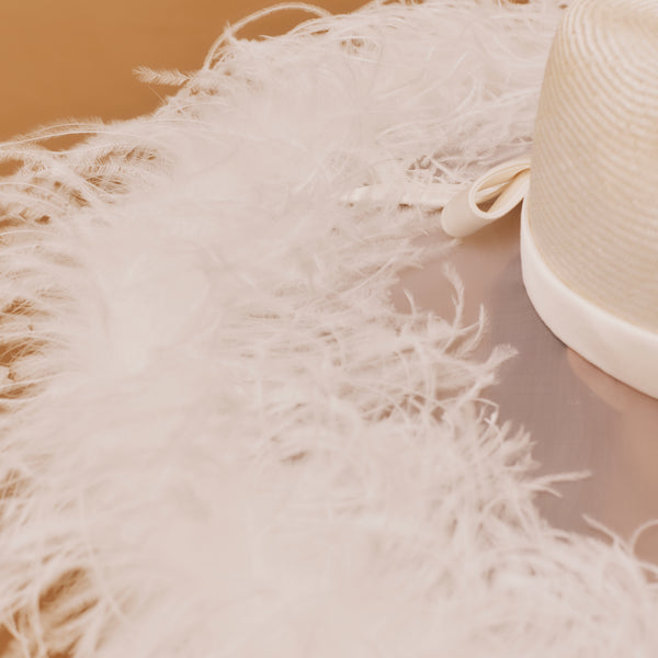 Close-up of a fluffy white pillow with a straw hat on a beige background