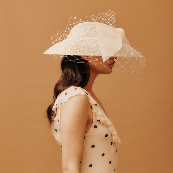 Woman wearing a white lace hat against a brown background