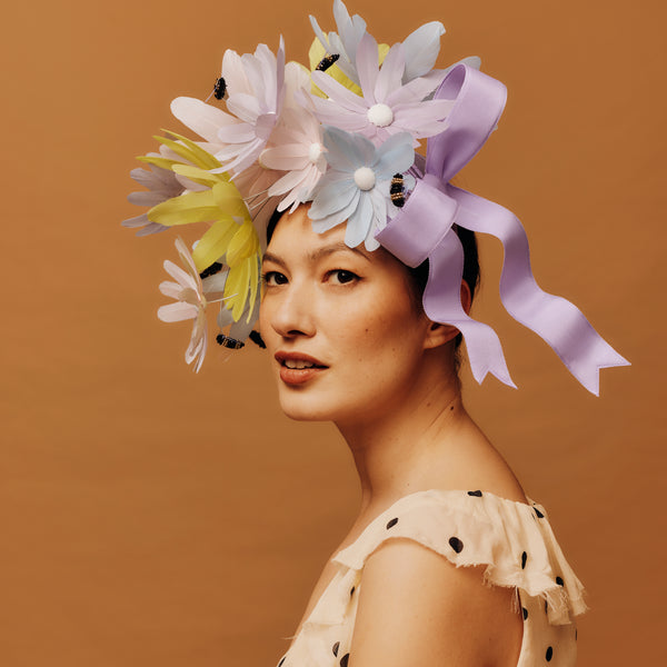 Woman wearing a colorful floral headpiece against a brown background