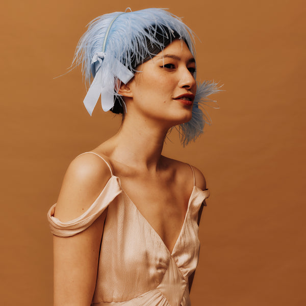 Woman wearing a decorative headpiece with feathers against a brown background