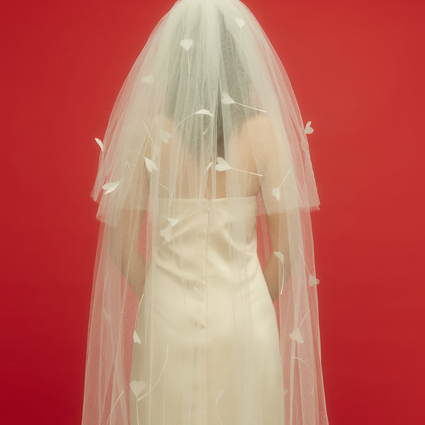 Awon Golding floor-length ivory white tulle veil with hand-cut heart shaped goose feathers. Back view of veil