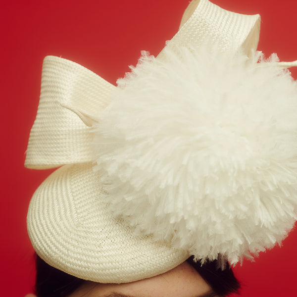 Awon Golding Ivory white straw button hat with giant ostrich pom pom and straw bow at the back. modern milliner. close-up